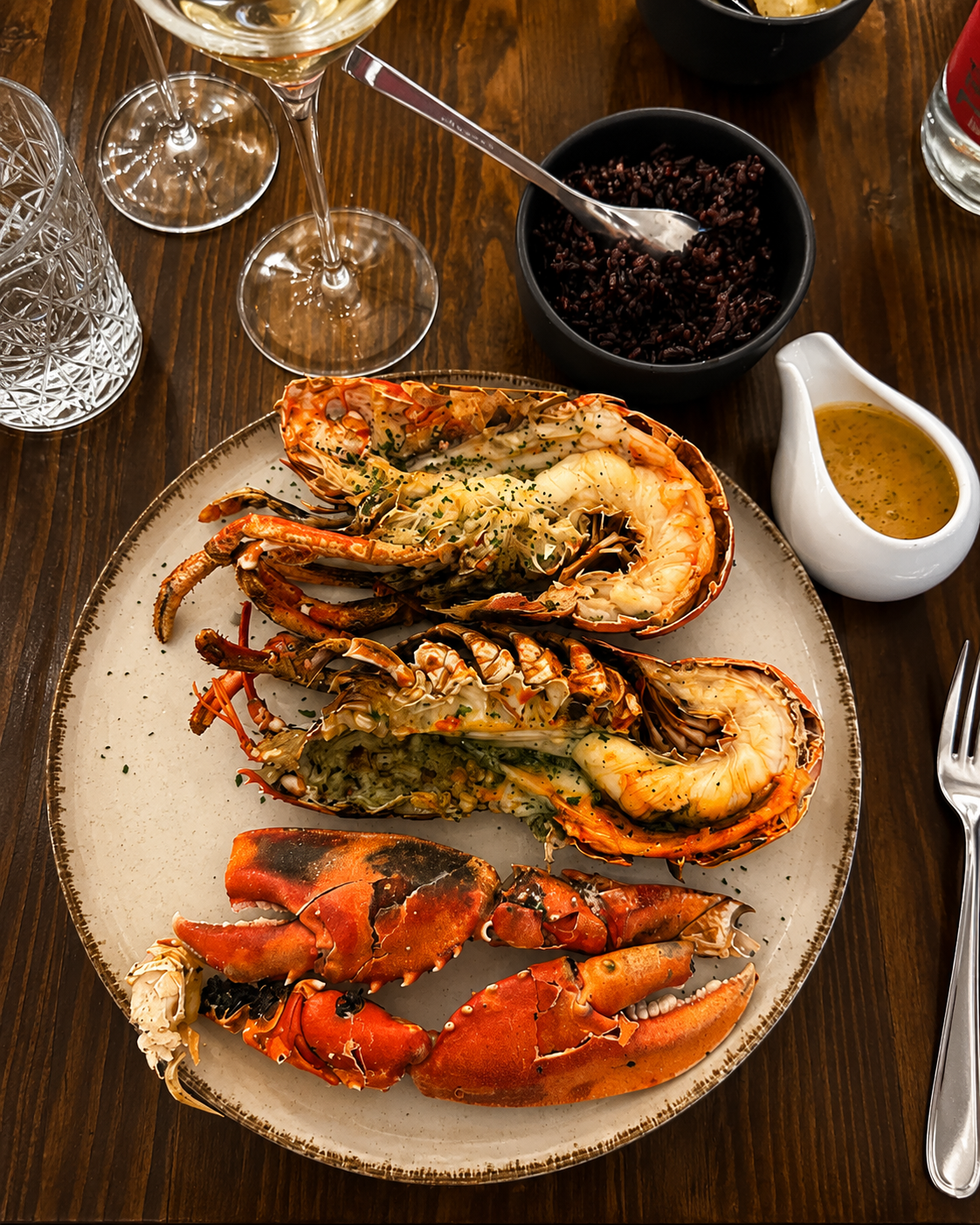 Langoustes grillées dressées à l'assiette, riz noir et sauce